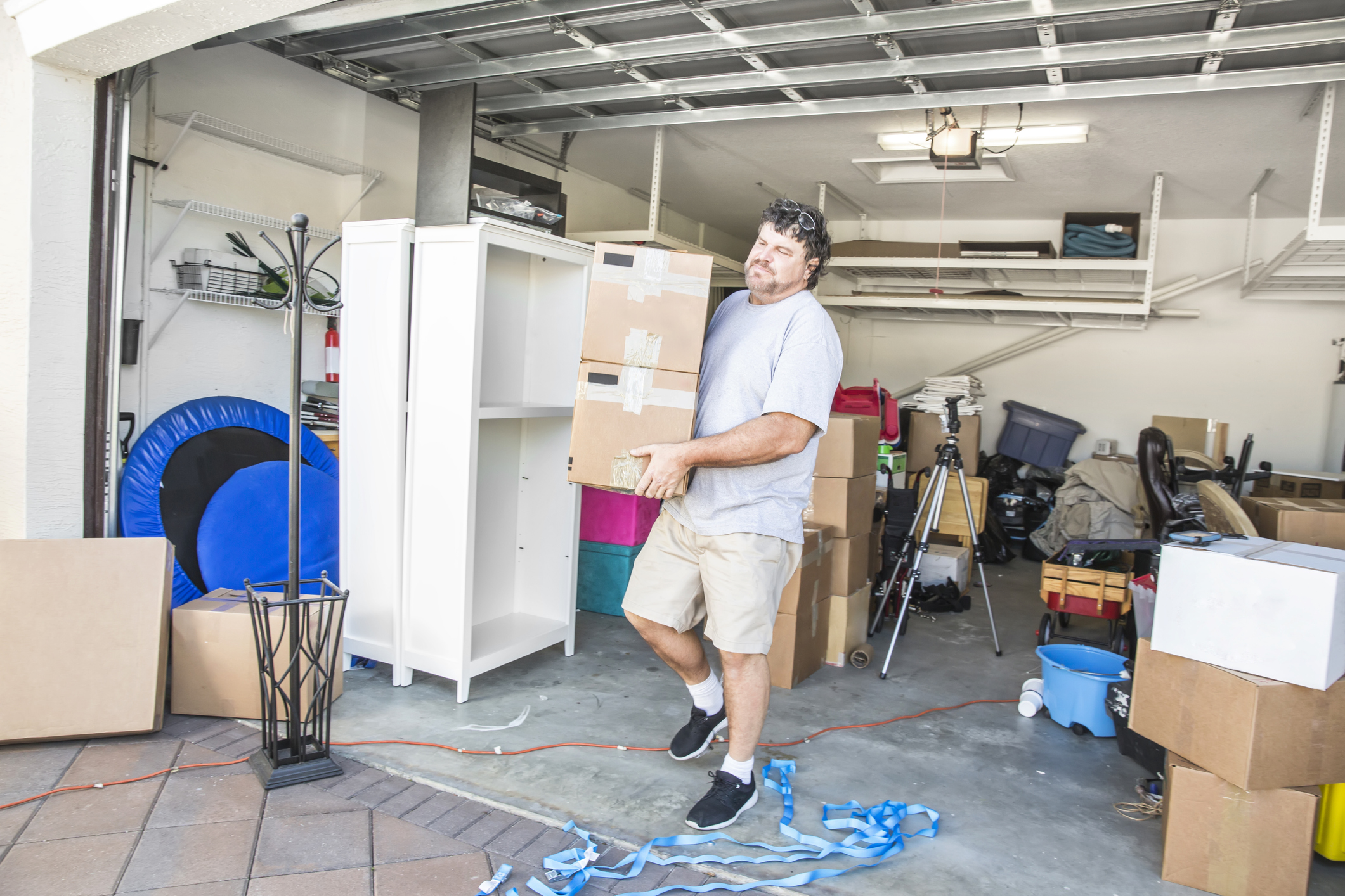 man moving boxes out of a cluttered garage