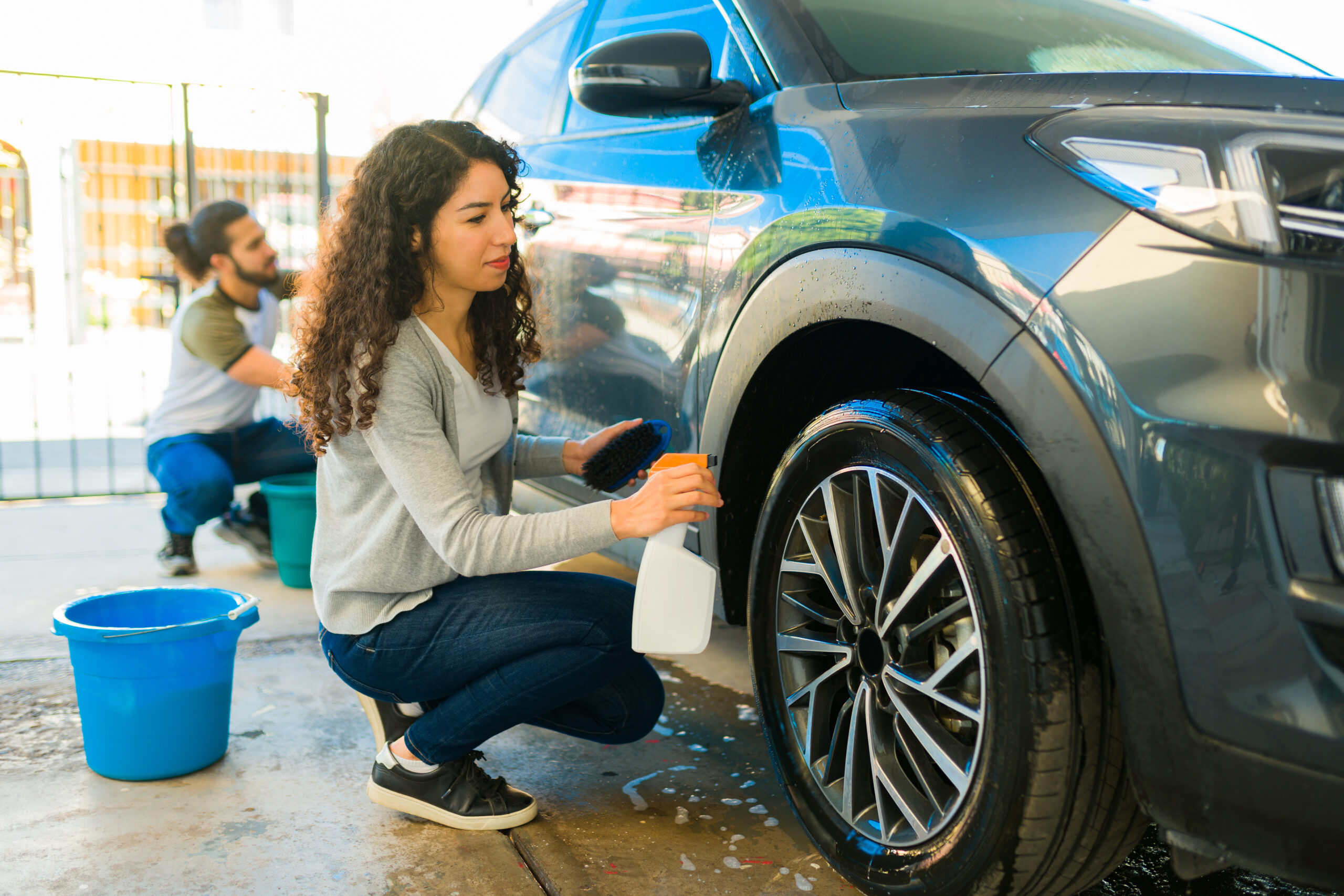 Young woman cleaning car tire