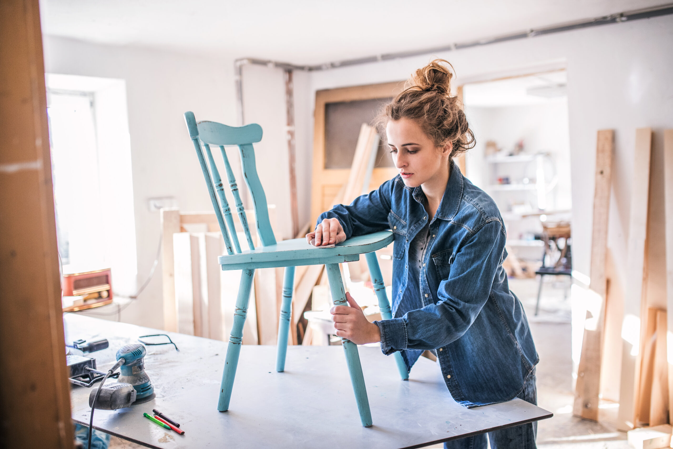 young woman putting together old wooden chair