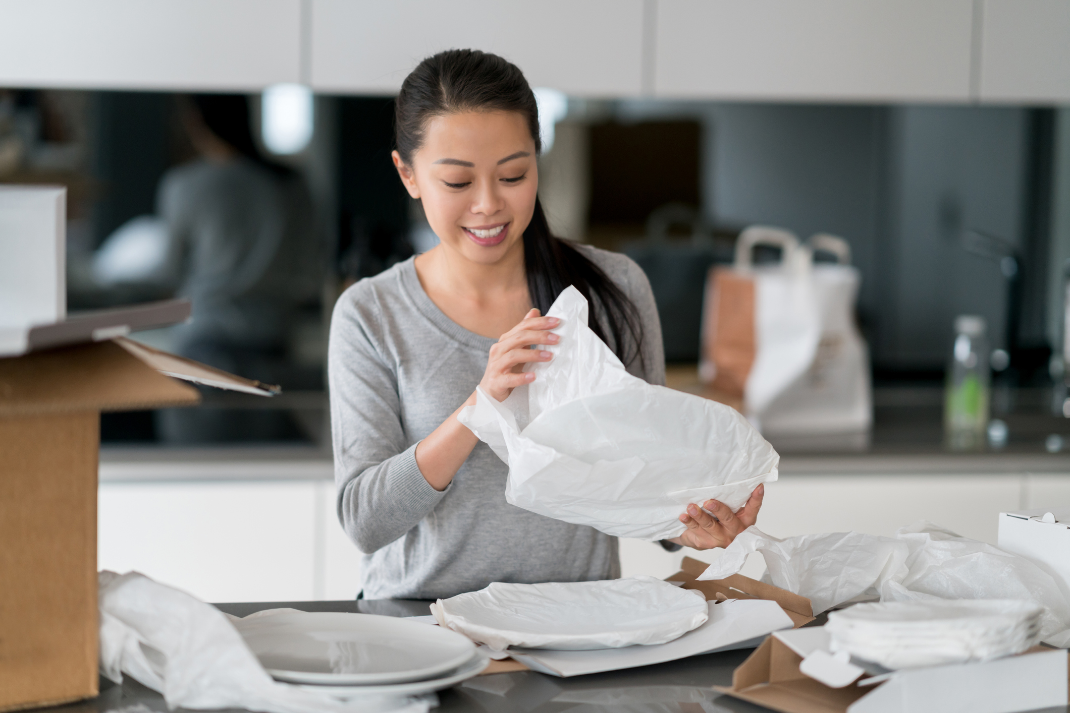 Asian woman packing things while moving home to show how to pack china for moving