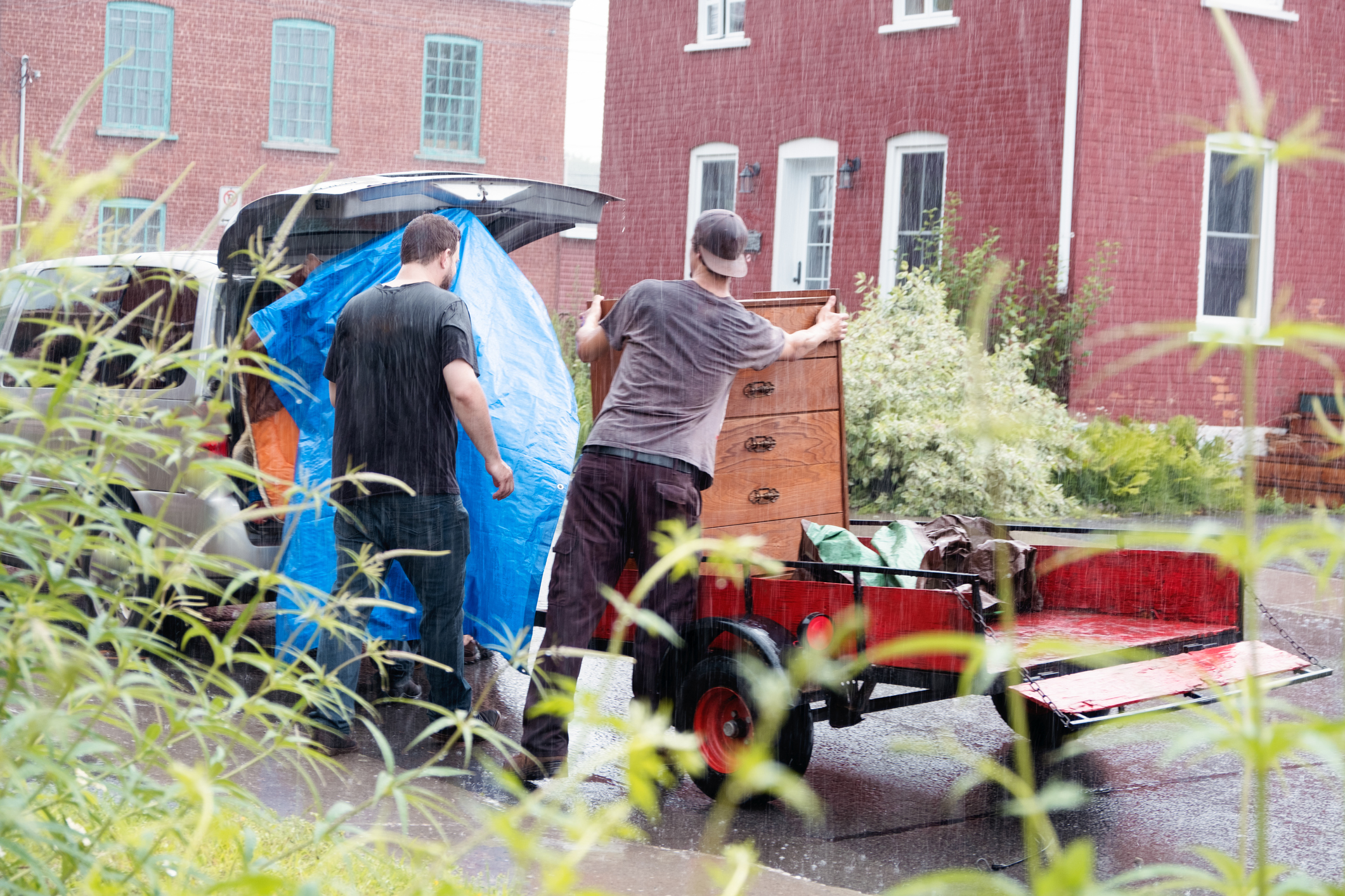 2 men moving in the rain loading furniture and boxes