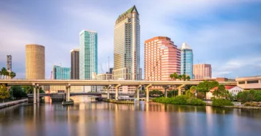 Tampa skyline with four tall glass buildings and an interstate over reflected in the water