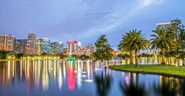 Orlando skyline at dusk with reflections of buildings and greenery in the water
